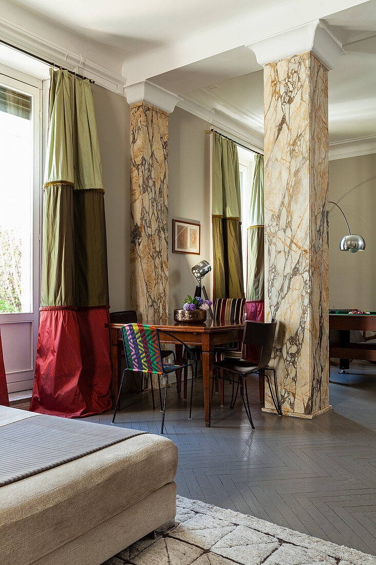 Wooden table and chairs in front of marble chairs and tri-coloured curtains