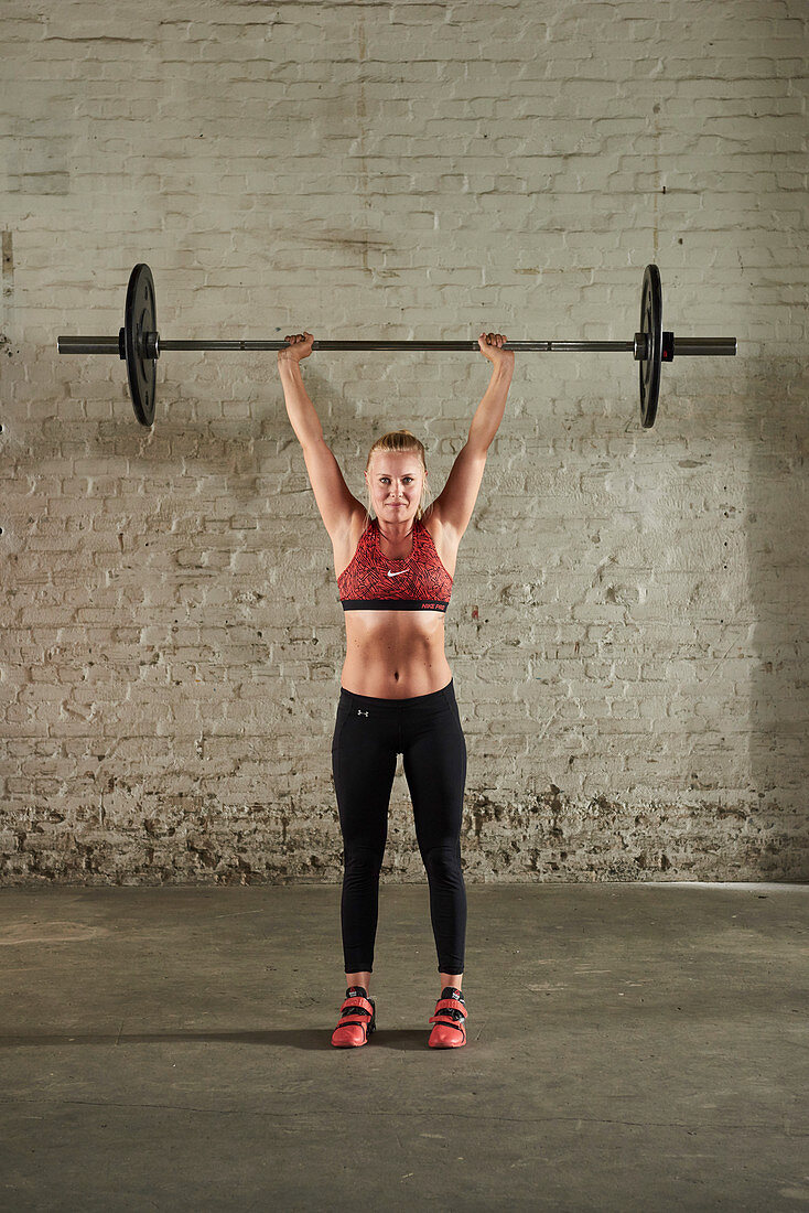 A young woman pressing a barbell