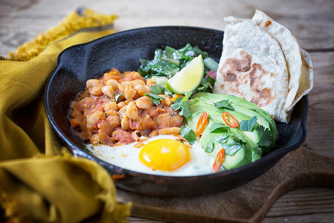 Frying pan with Beans, Avocado, Tomatoes, Eggs and Bread