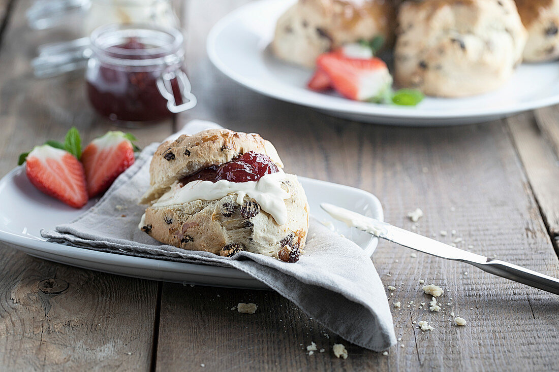 Scones with jam, cream and fresh strawberry on a rustic board