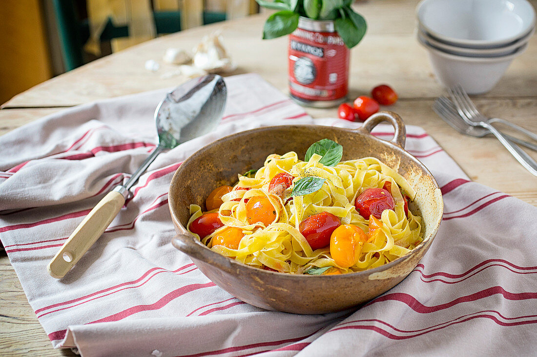 Rustic bowl of tomato pasta on a kitchen table covered with striped red linen
