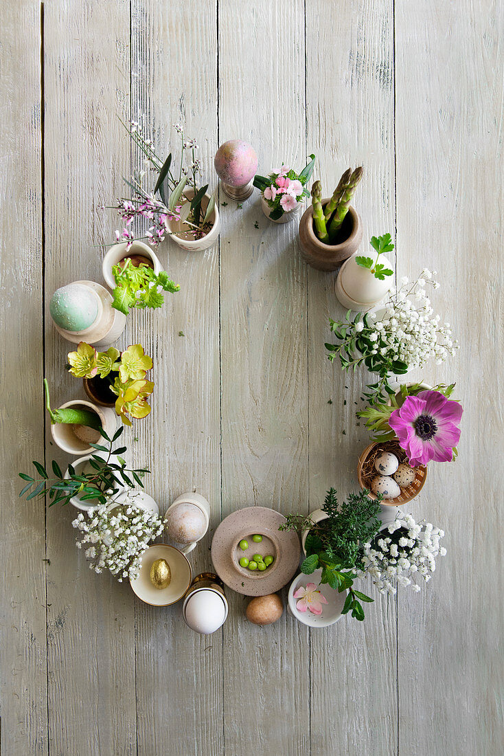 Blumen, Gemüse und Eier kreisförmig arrangiert als österliche Dekoration