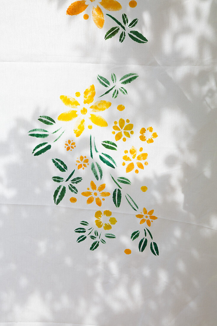 Yellow flowers and green leaves painted on white fabric
