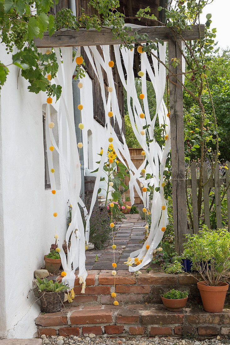 Fadenvorhang mit Pompongirlanden am Durchgang im Garten