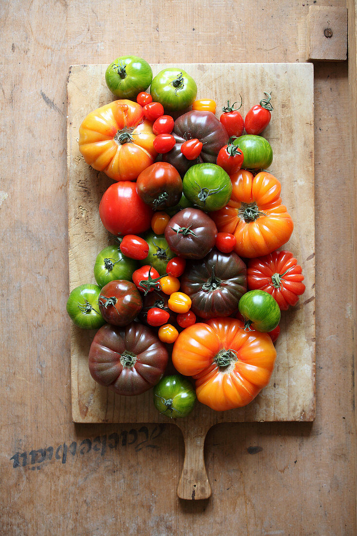 Various types of tomatoes on a wooden cutting board