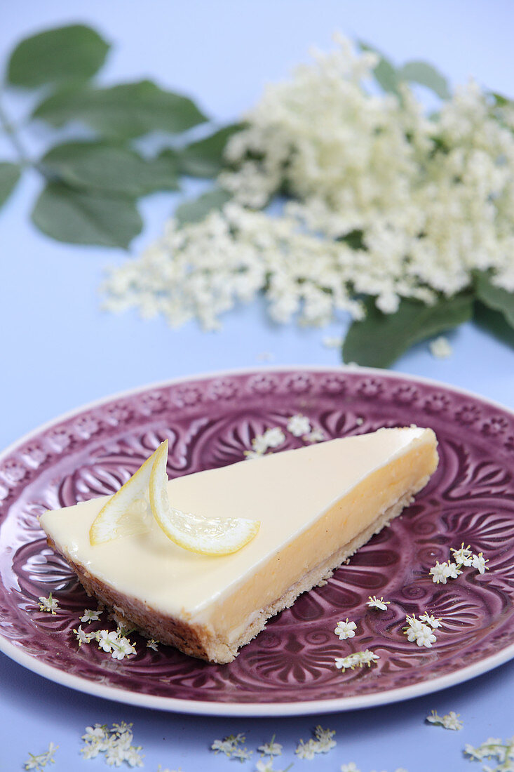 A piece of gin and tonic lemon tart with elderflowers