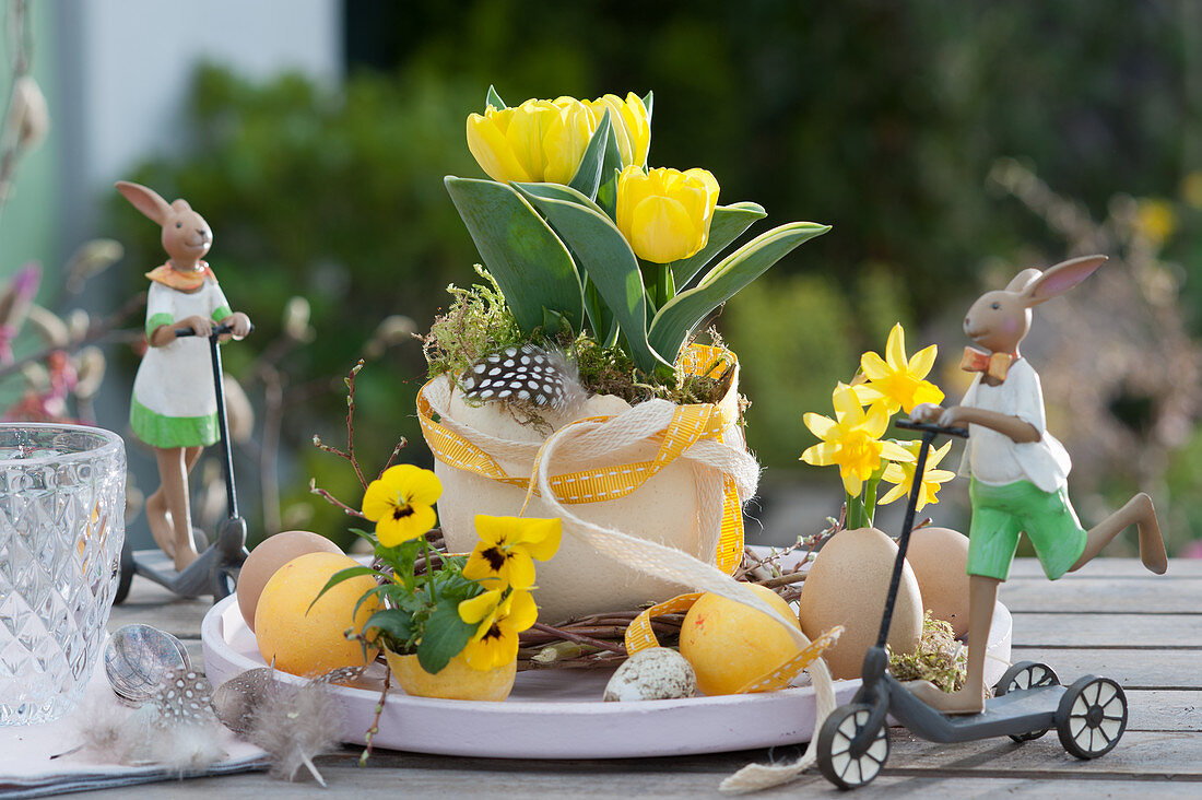 Easter table decoration with tulip and horn violets, Easter eggs and Easter bunnies