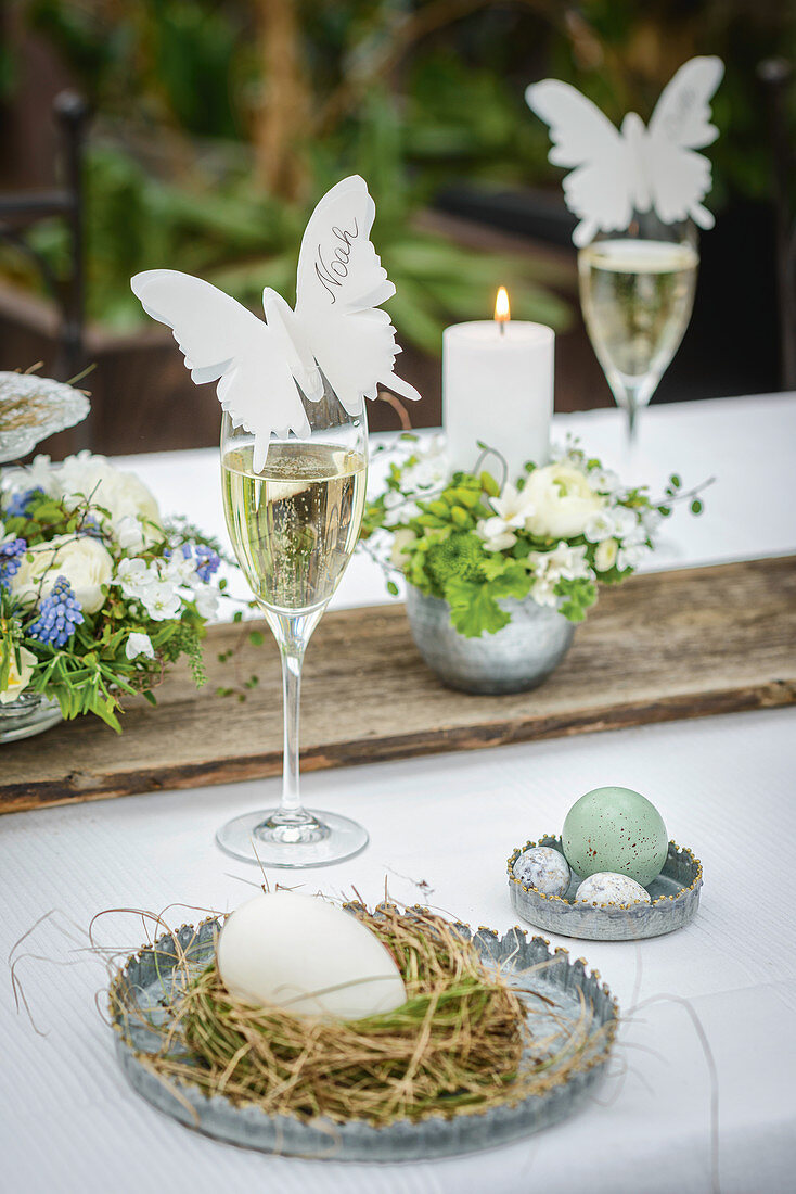 Butterfly-shaped place card on glass of Prosecco on Easter dining table