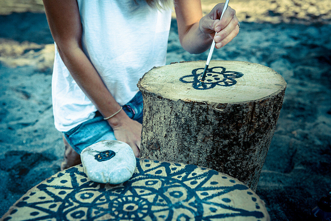 Holzklotz wird mit schwarzem Mandala bemalt