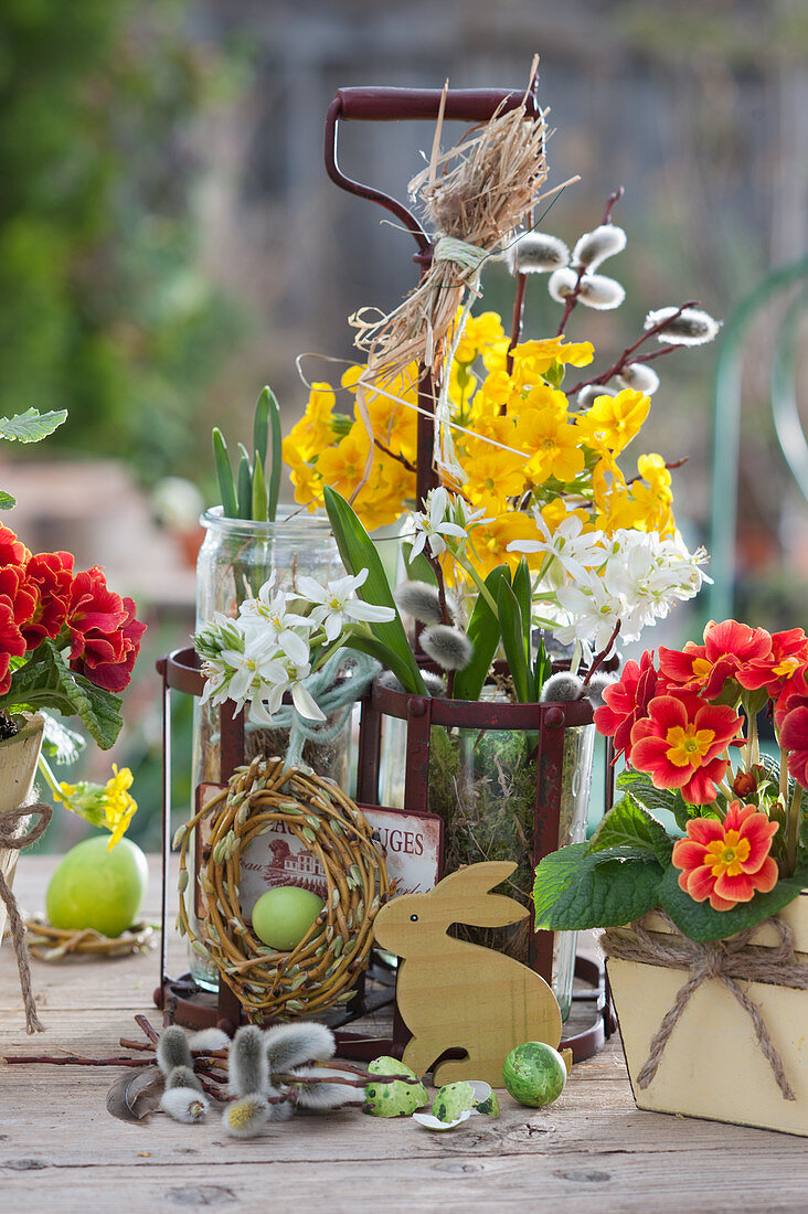 Small spring decorations with primroses, willow wreaths and pussy willow in a milk bottle carrier, Easter eggs and bunny