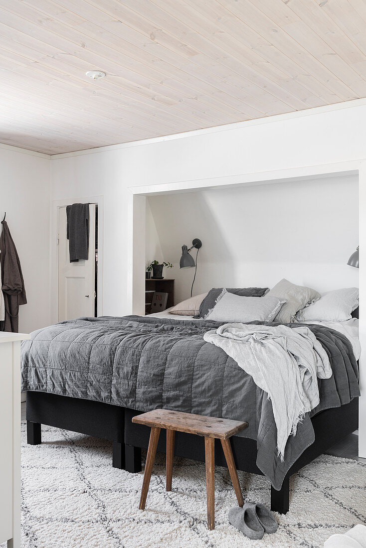 Schlafzimmer in Grautönen mit Bett in Zimmernische unter Schräge