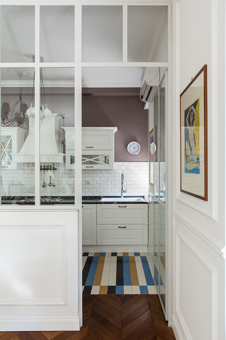 View through glass wall into white country-house kitchen in period building