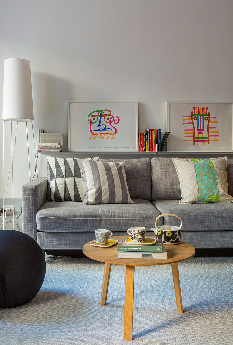 Round coffee table in front of grey sofa with graphic patterns on scatter cushions