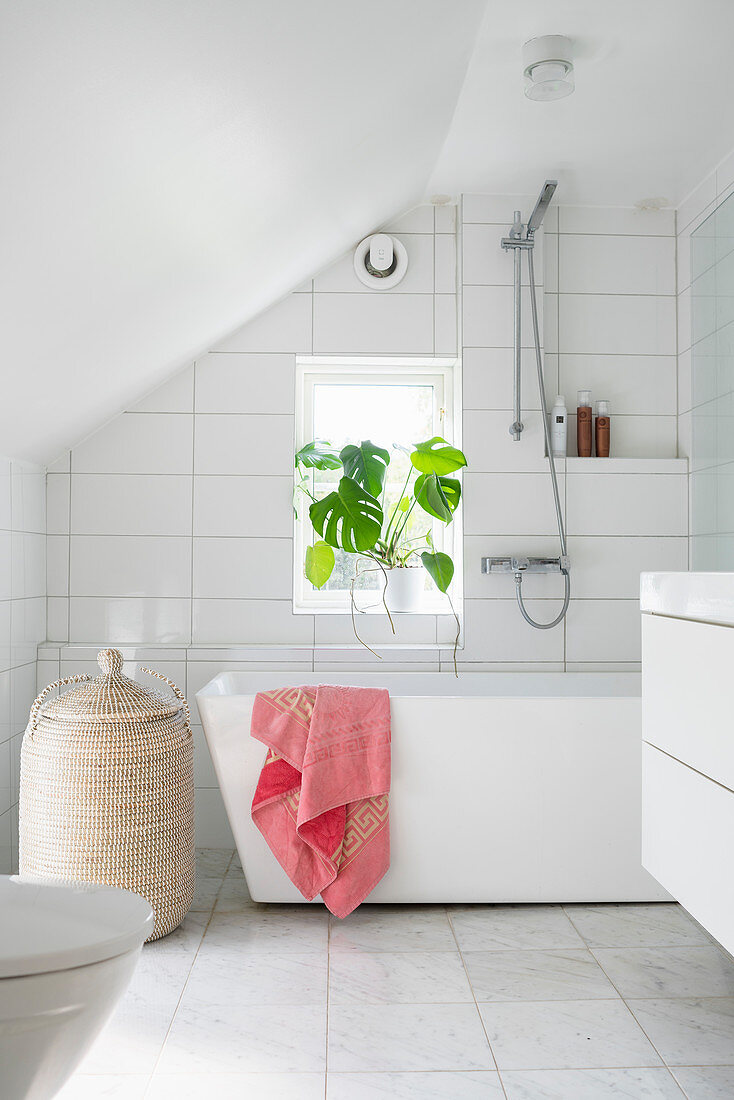 Weißes Badezimmer mit Badewanne und Marmorboden im Dachgeschoss