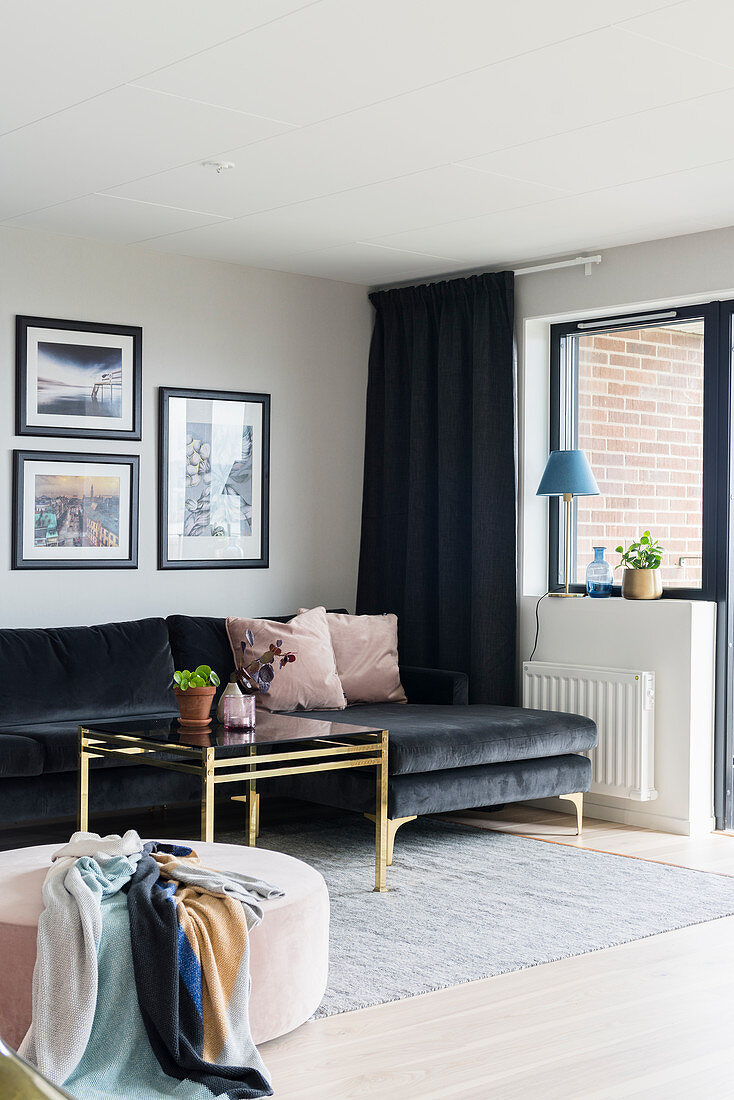 Black, velvet chaise sofa, brass coffee table and pink pouffe in living room