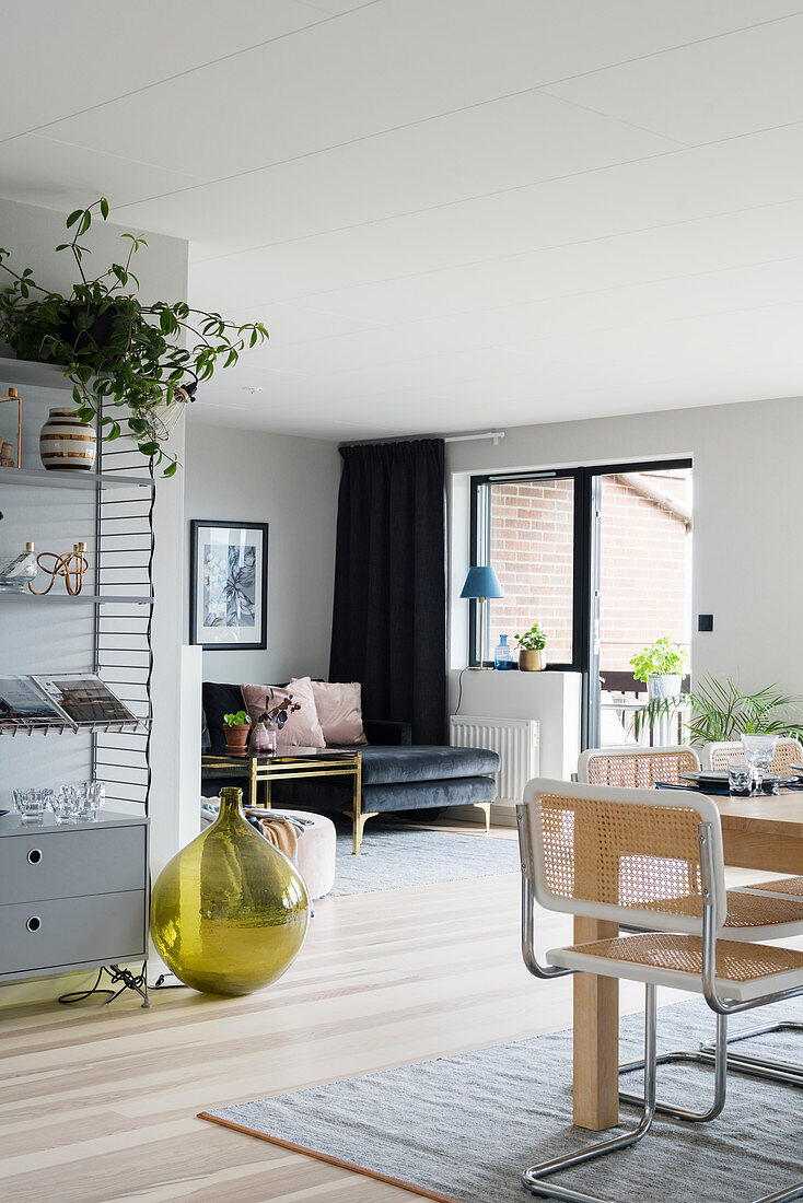 Black velvet sofa and pale dining table with cantilever chairs in L-shaped interior