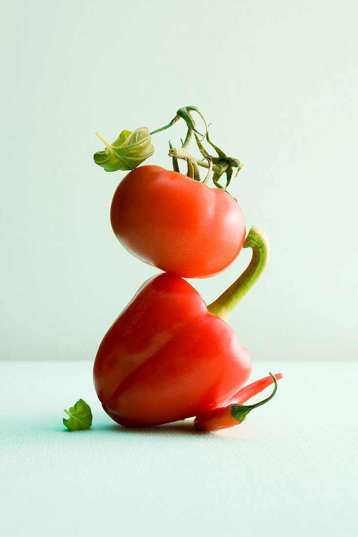 A tomato, a red pepper and a chilli pepper stacked on top of each other