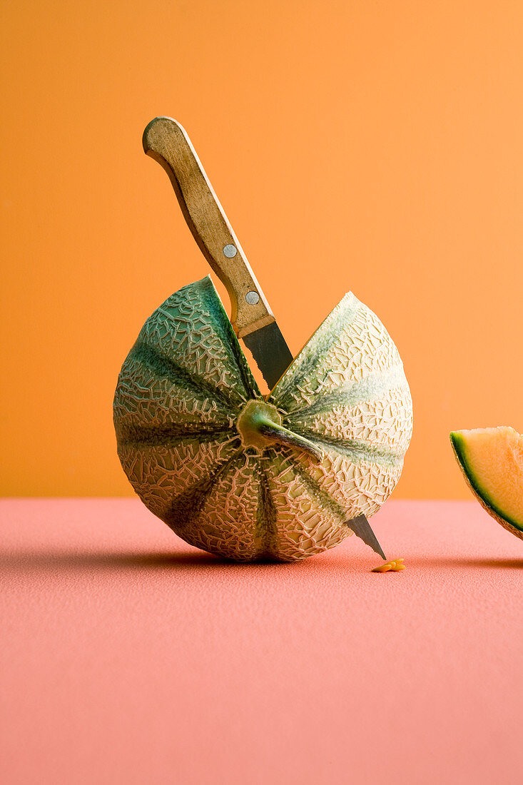 A sliced melon with a knife