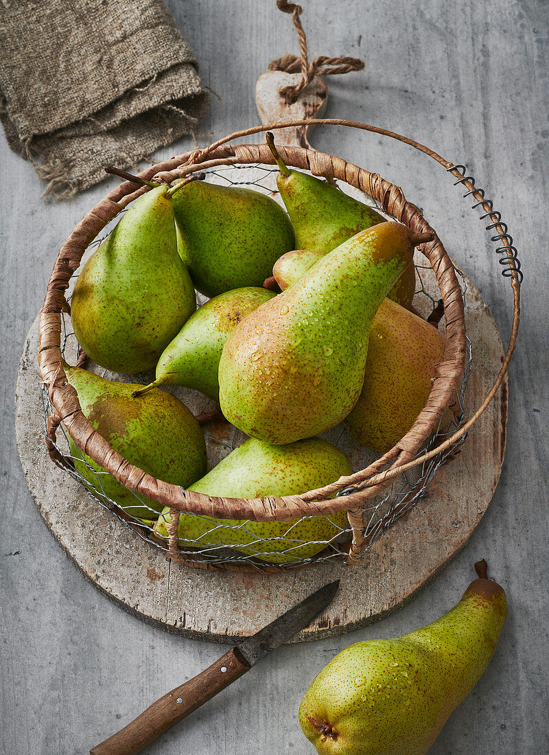 Pears in a wire basket with a peeler
