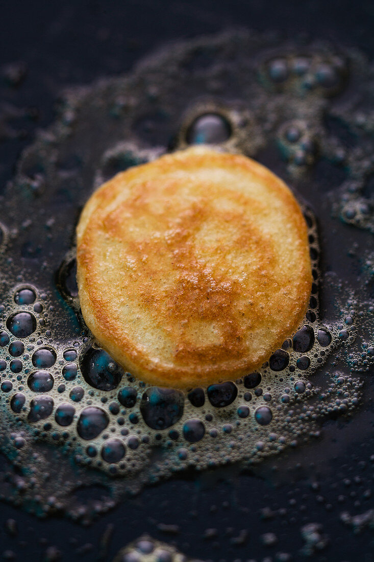 A blini being fried in a pan