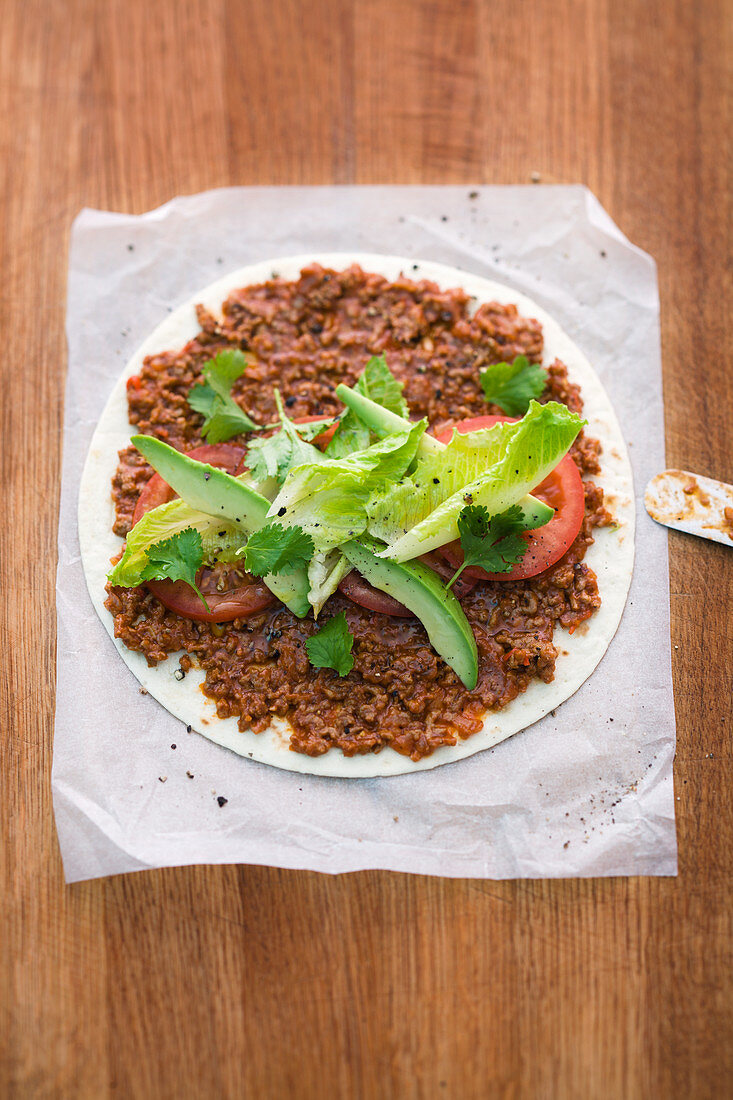 A burrito with minced meat and avocado