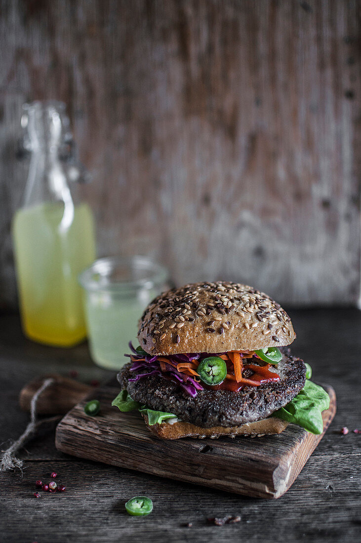 Vegan black bean burger served in whole grain bun with red cabbage, carrot and jalapeno