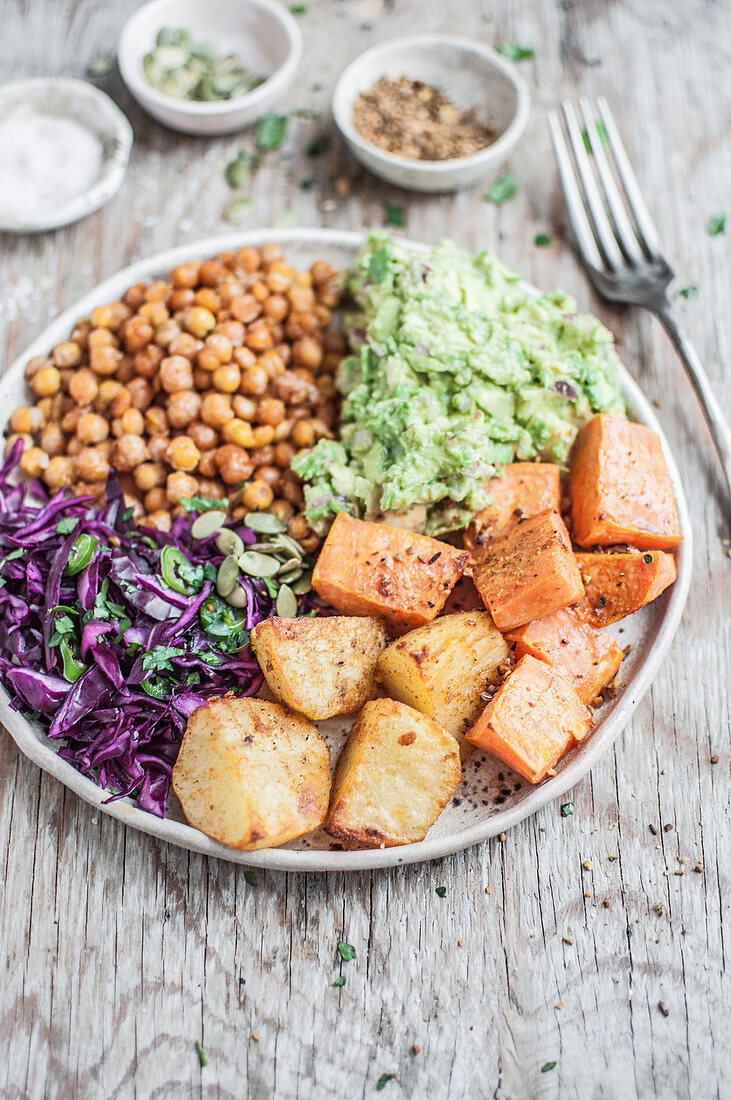 Vegan Buddha bowl - spicy roasted chickpeas and potatoes with cabbage slaw and guacamole