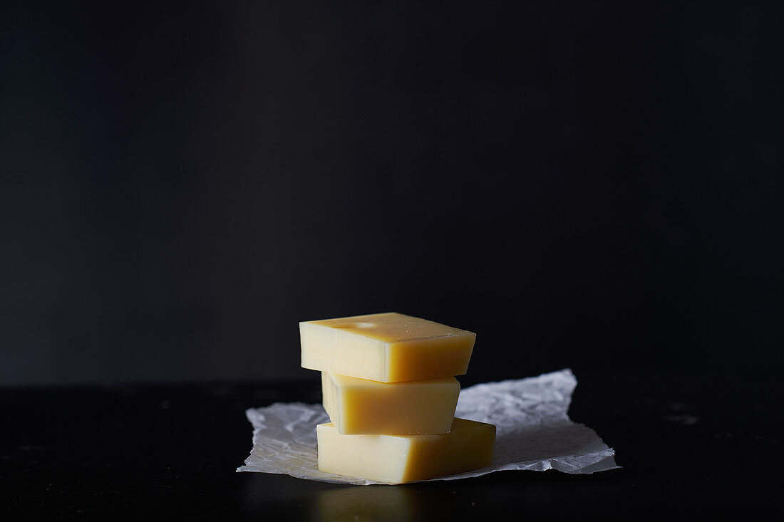A stack of three slices of Emmental cheese