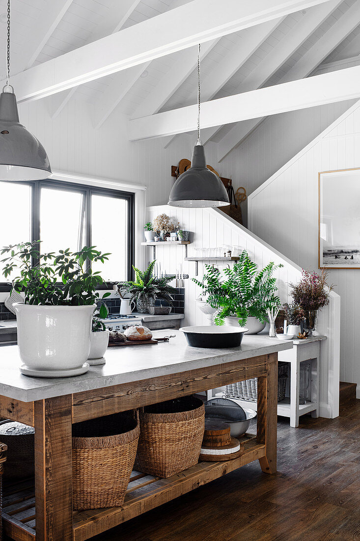 Plants and baskets on a rustic wooden table in the open kitchen