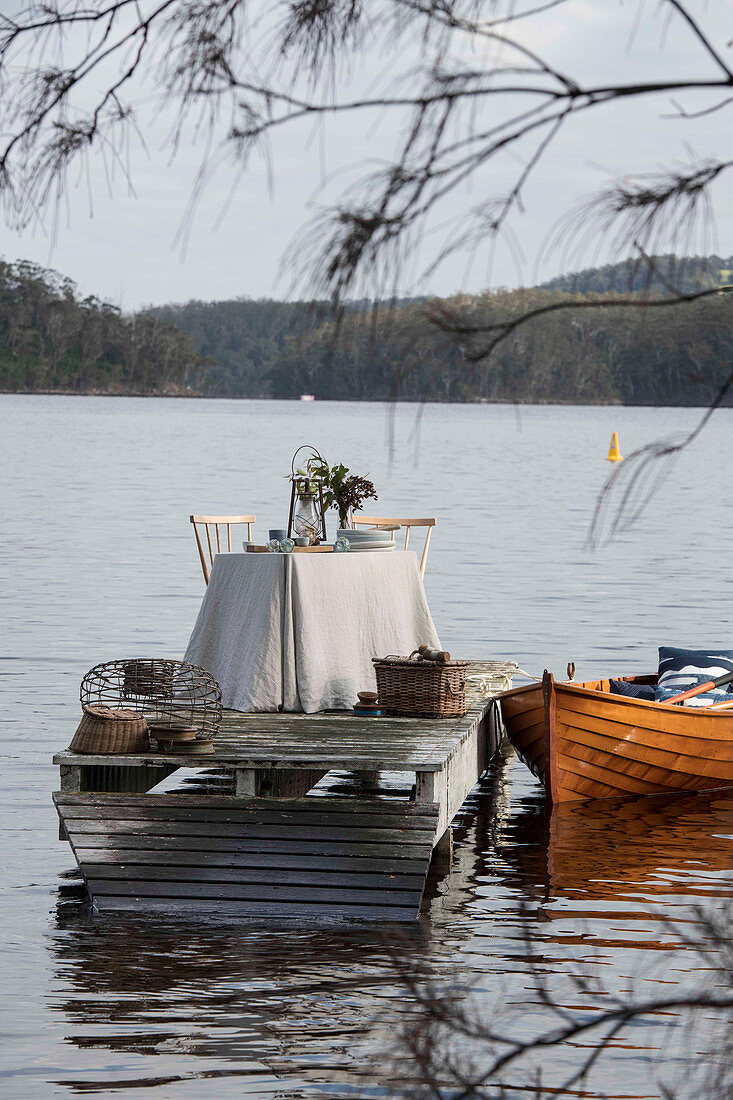 Gedeckter Tisch auf einem Steg und Boot auf einem See