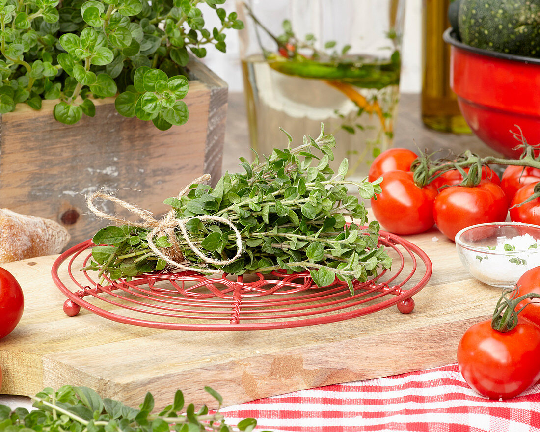 A bunch of fresh oregano with a pot holder on a wooden board