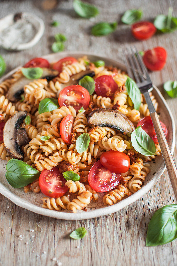 Fusilli pasta with pesto rosso, mushrooms, tomatoes and fresh basil