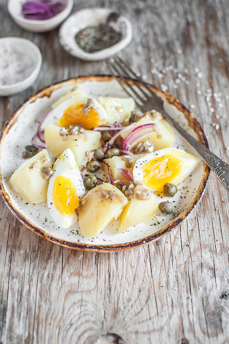 Kartoffelsalat mit gekochtem Ei, roten Zwiebeln und Kapern
