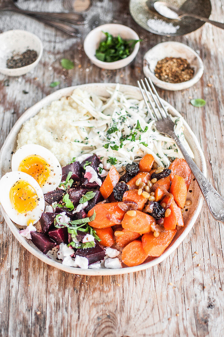 Winter buddha bowl - Stewed carrot with raisins, beetroot salad with goast cheese and mint, boiled egg, millet and celery root slaw