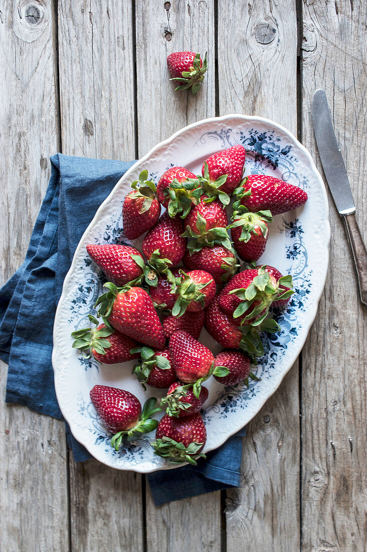 Frische Erdbeeren auf Vintage-Servierplatte mit Serviette und Messer