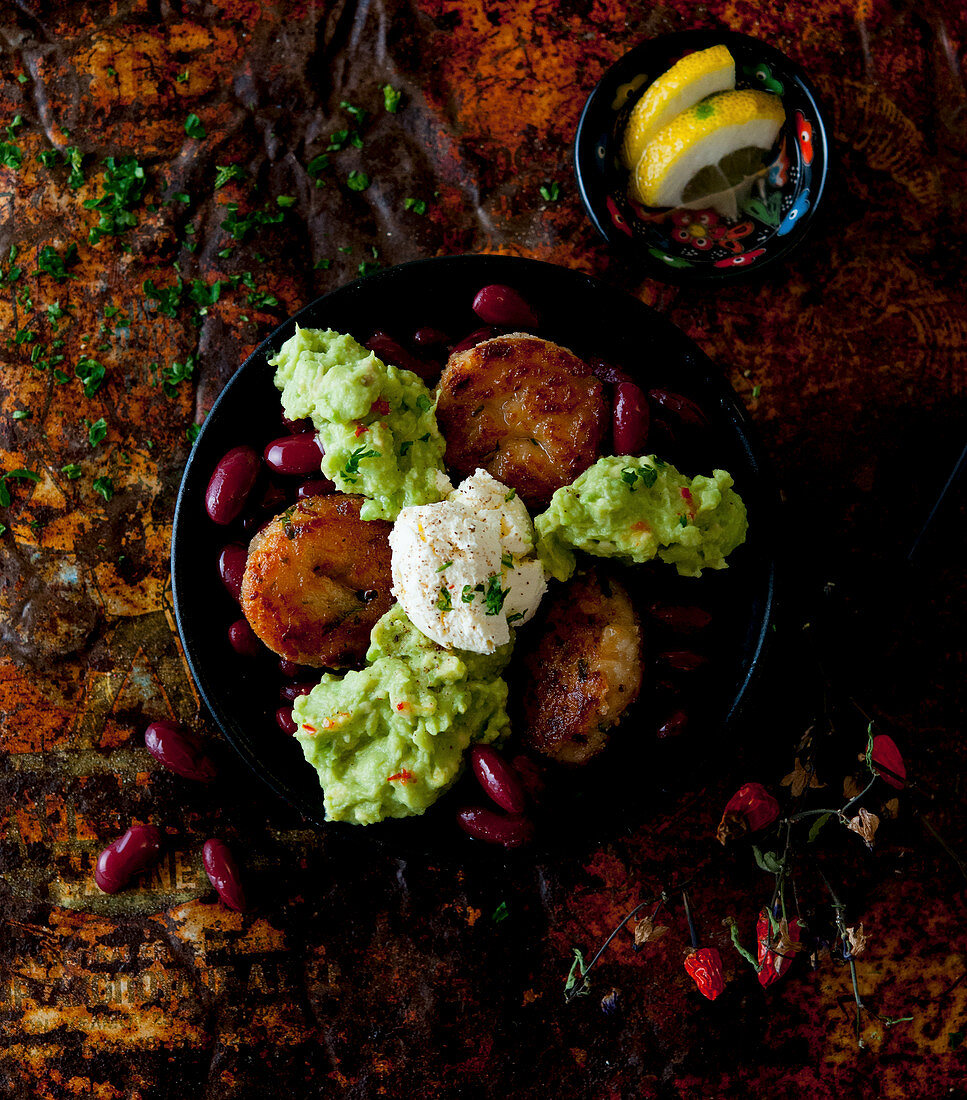 Bowl mit Gemüsebratlingen, Kidneybohnen, Guacamole und Frischkäse