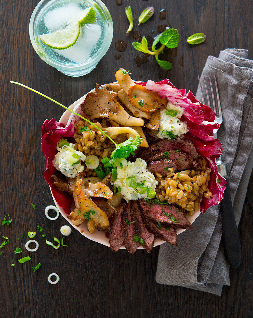 Bowl mit Rindersteak, Austernpilzen, Grünkern, Kräutercreme und Radiccio