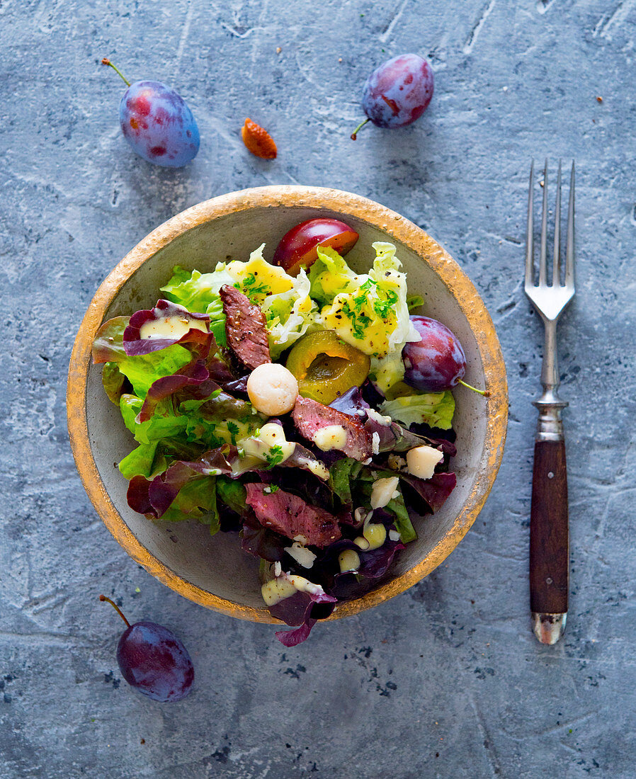 An autumnal salad with damsons, beef fillet and macadamia nuts