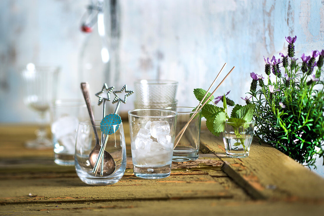 A bar arrangement with ice cubes, bar utensils, mint and lavender