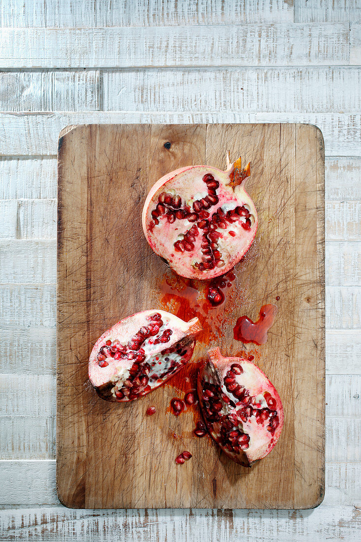 A sliced pomegranate on a wooden chopping board