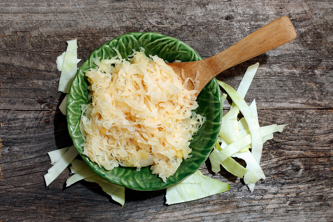 Sauerkraut on a green plate with a wooden spoon