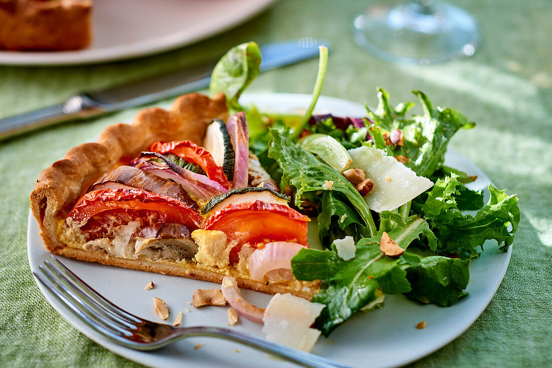 Vegetable tart and a green salad with young horseradish leaves and Parmesan cheese