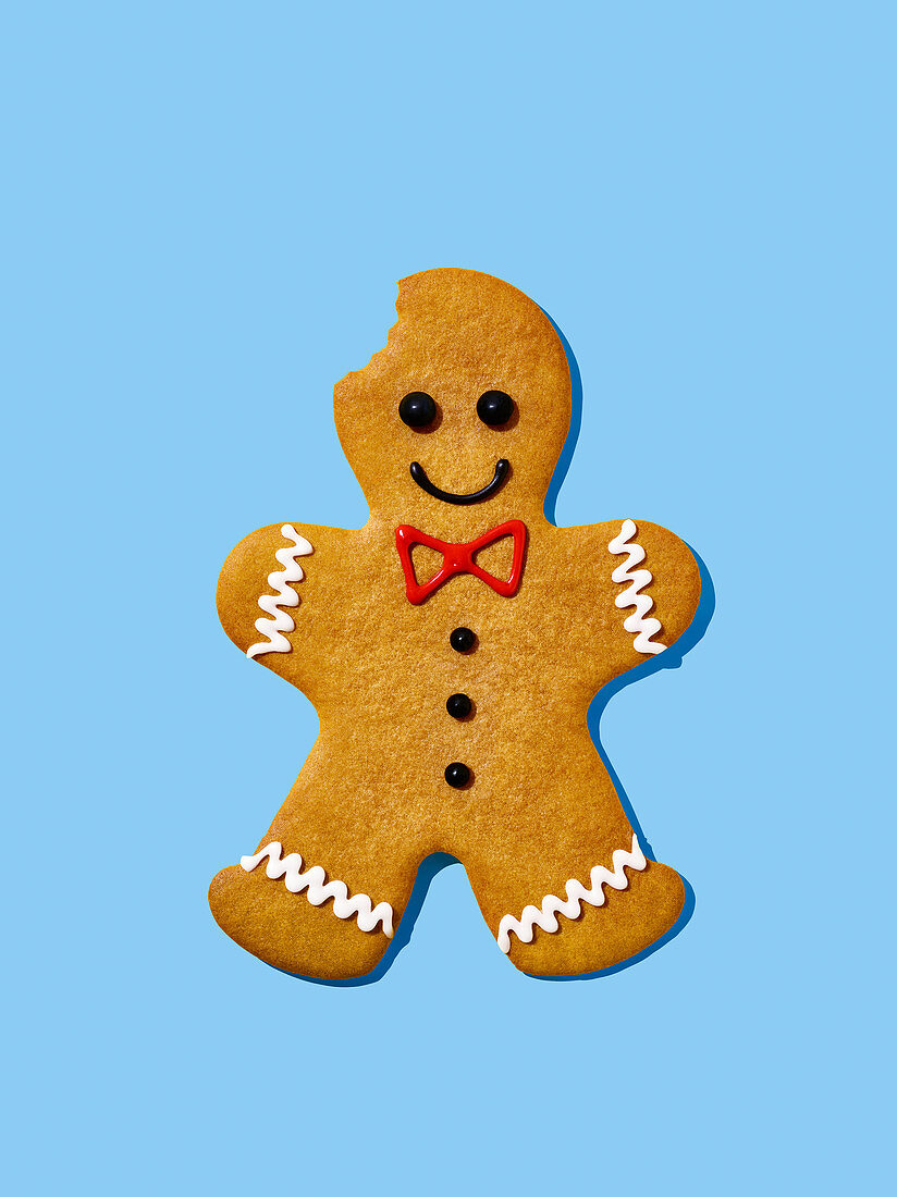 A gingerbread man with a bite taken out on a light blue surface
