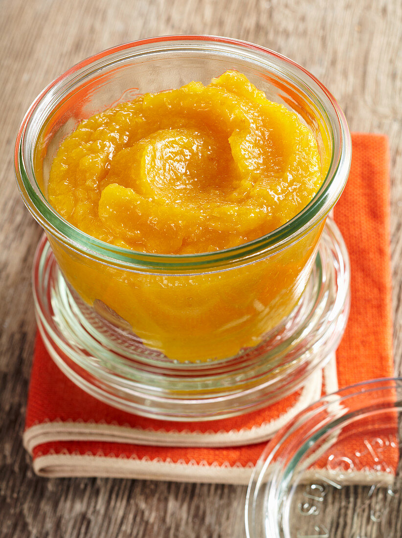 Homemade peach purée in a preserving jar on a fabric napkin