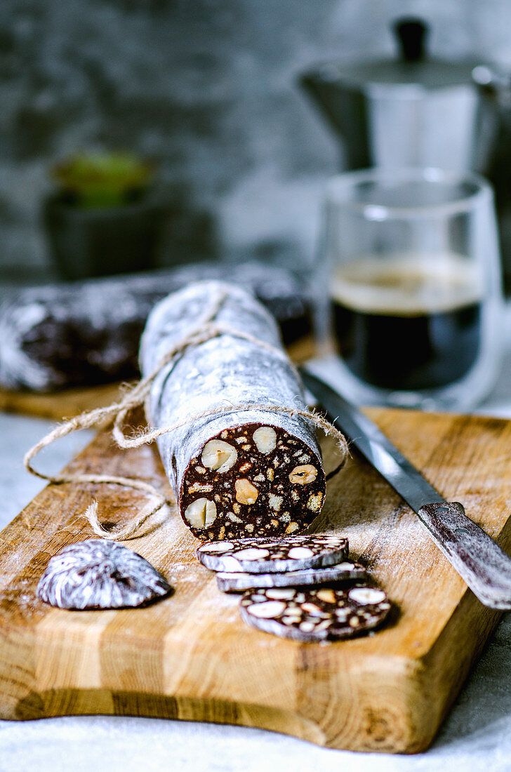 Chocolate sausage with biscuits and hazelnuts, cut on a wooden board