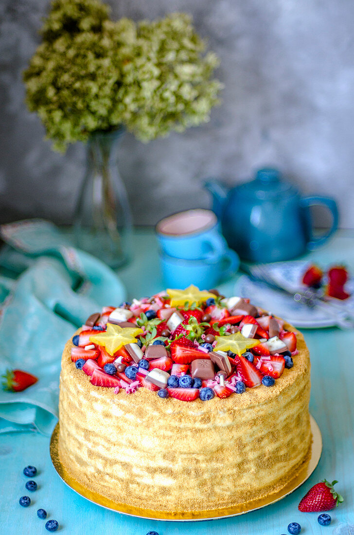 Honey cake decorated with berries, chocolate pieces and starfish stars