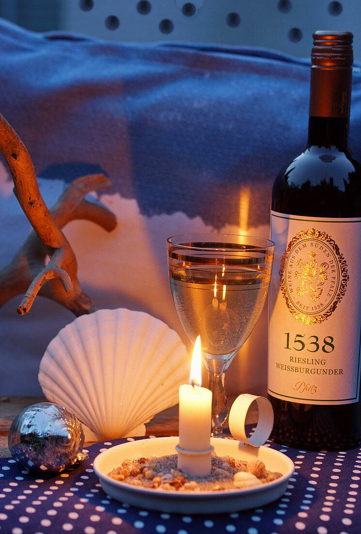 Twilight scene with white wine, candlelight and maritime ornaments
