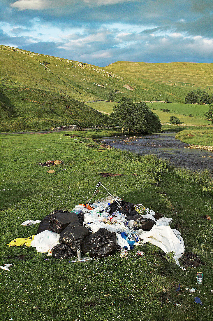 Fly tipping next to a river, Cumbria, UK