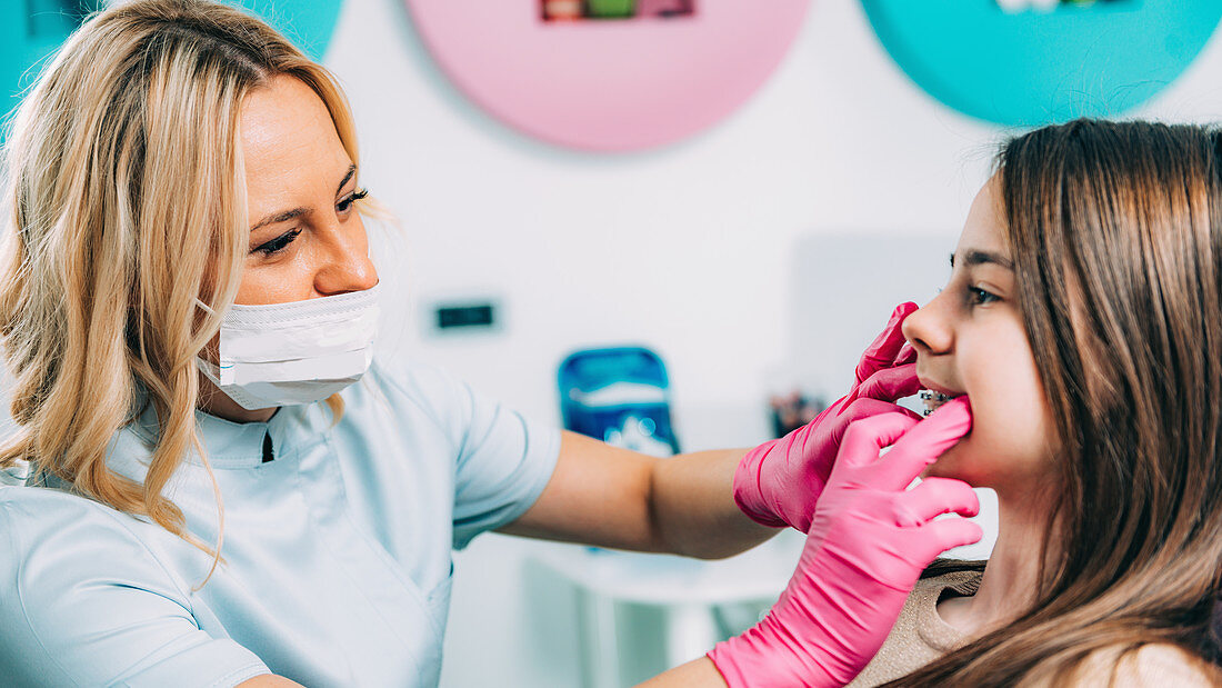 Orthodontist fixing girl's dental braces