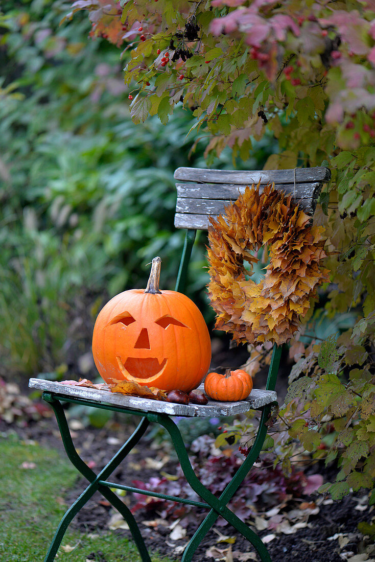 Halloween pumpkin and wreath of sycamore leaves on garden chair